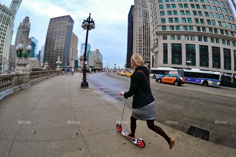 Woman riding scooter in a beautiful city of Chicago, Usa