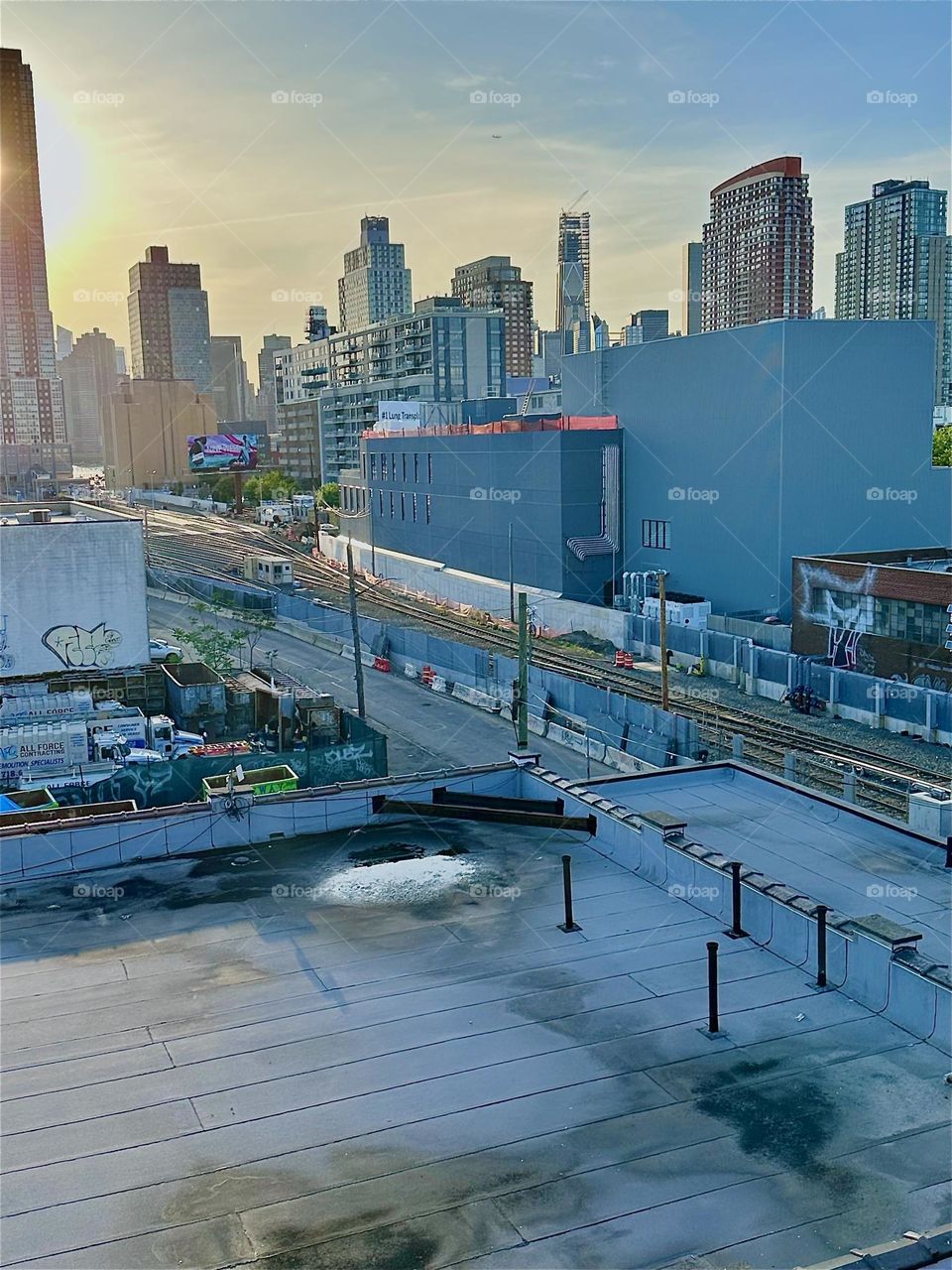 From the top of the “Pulaski Bridge” at “Newtown Creek” in LIC we overlook the “Long Island Railroad” tracks and “iFly” in the rectangular building, an indoor flight simulator akin to the free fall when parachuting. 2024. Hypnotic Productions
