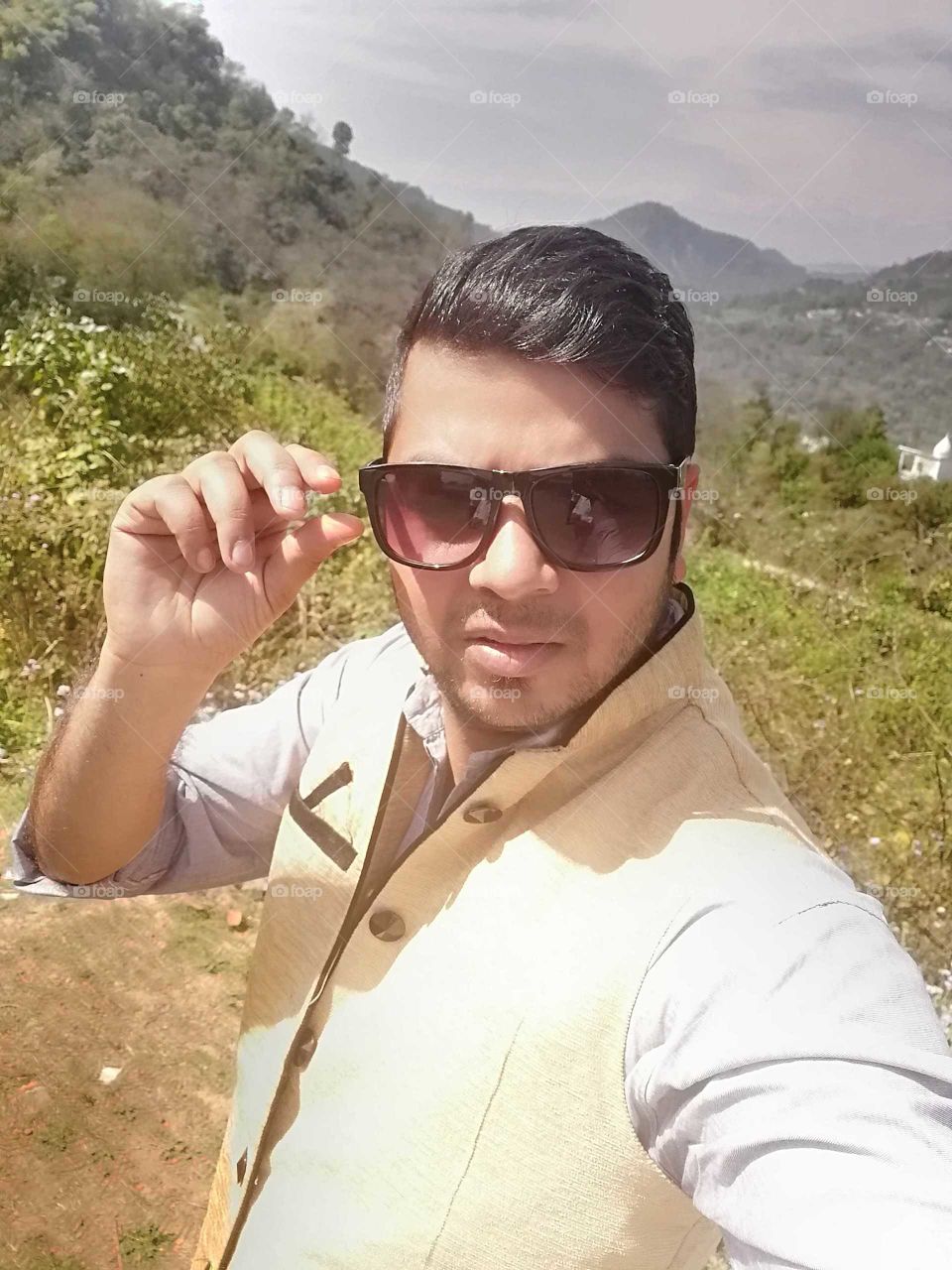 A gentleman with square summer sunglasses and green background.