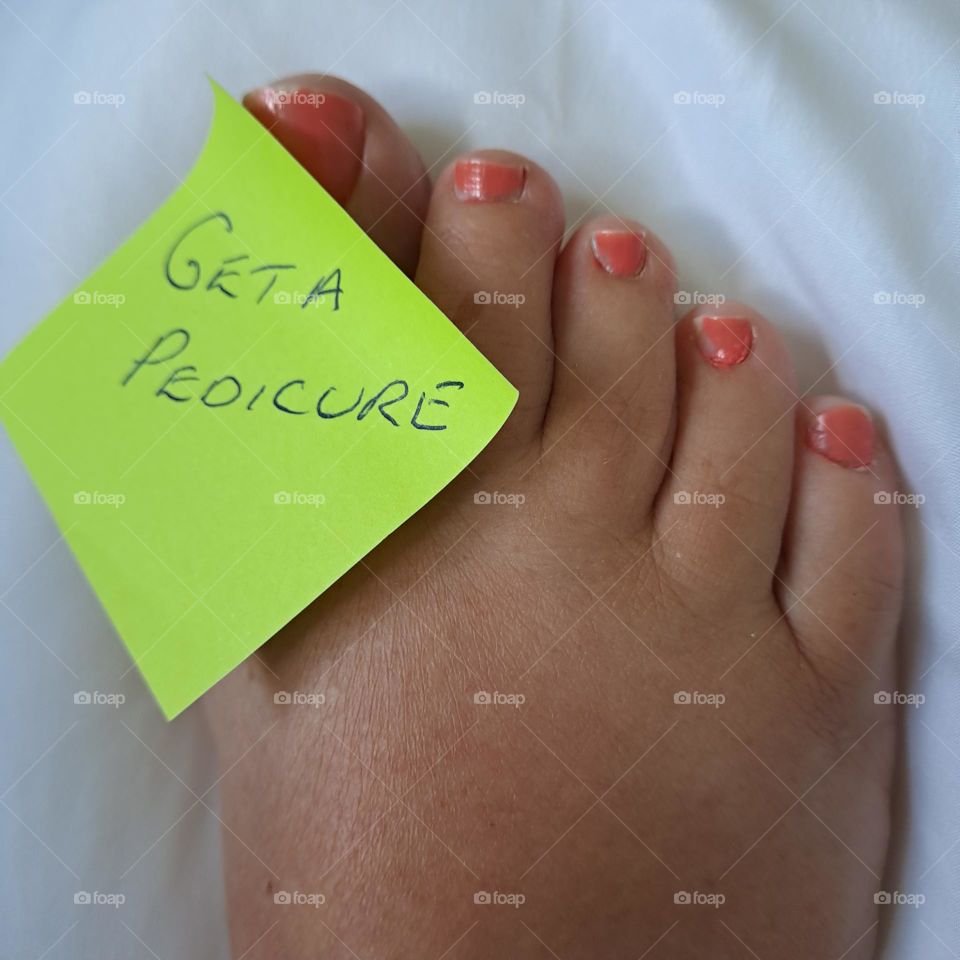 ladies foot. painted toenails. toes. sticky note reminder stuck on. pedicure.