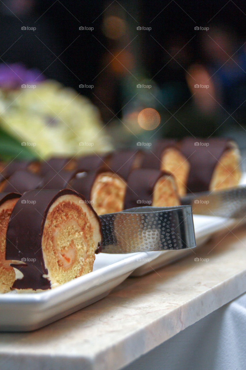 Dessert rolls covered in chocolate served on plates with tongs