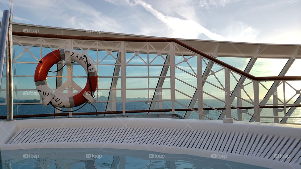 view from hot tub on cruise ship deck looking out through railing to blue ocean and cloudy sunny skies. Azamara cruise trip