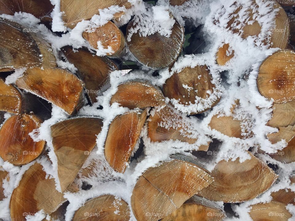 Pile of cut firewoods covered in snow