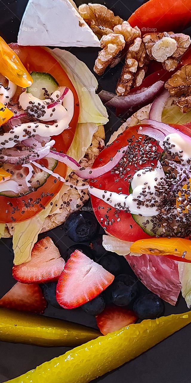 Closeup of two gourmet sandwiches with pickled gherkins, nuts, blueberries and strawberries