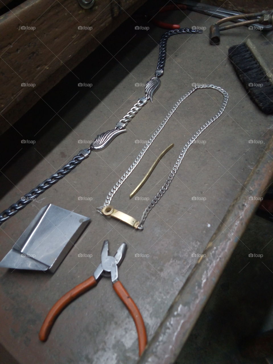 cajón de joyería con trabajos realizados en oro y plata y algo de la herramienta que se ocupa, como pinzas, cepillo y un pequeño recogedor