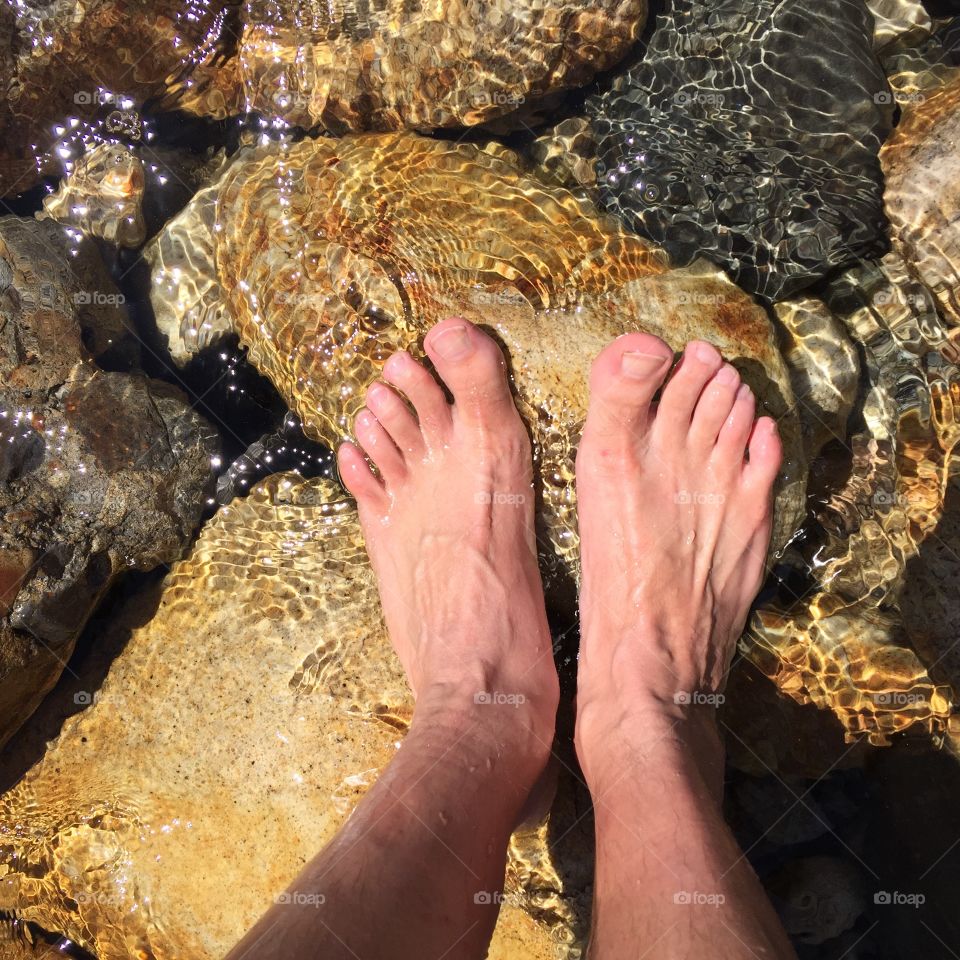 Males feet in clear water

