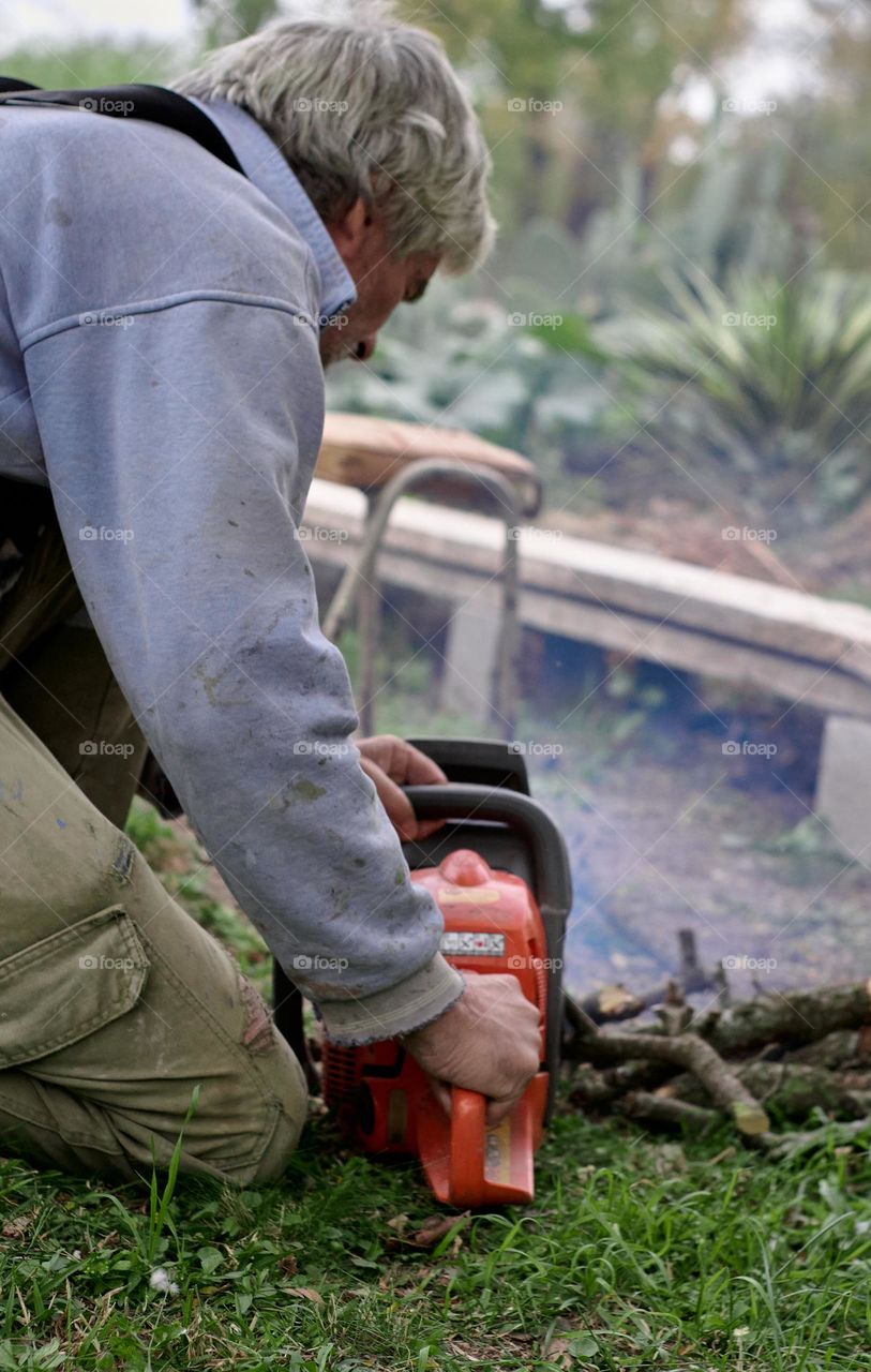 Man cuts firewood with a chainsaw in the middle of autumn, waiting for winter.