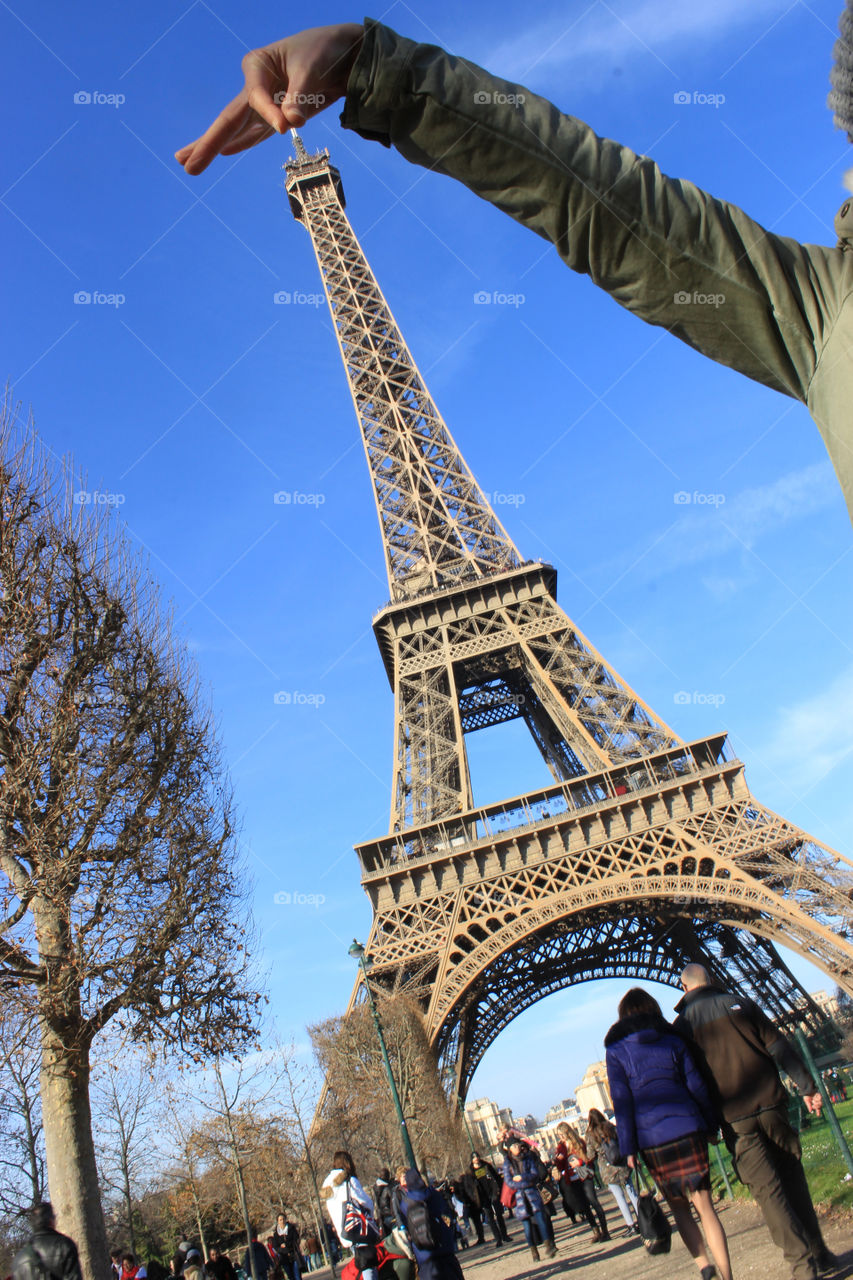 Hand holds the Eiffel Tower from the top