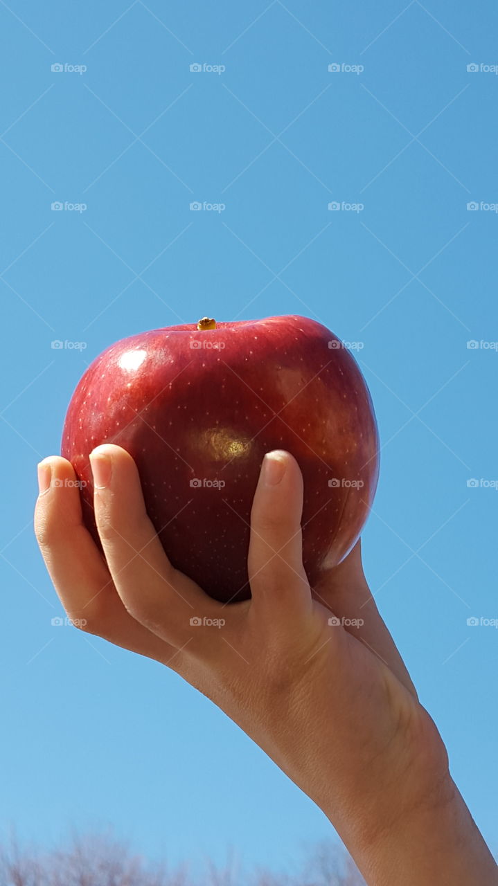Red apple in one hand at outdoor