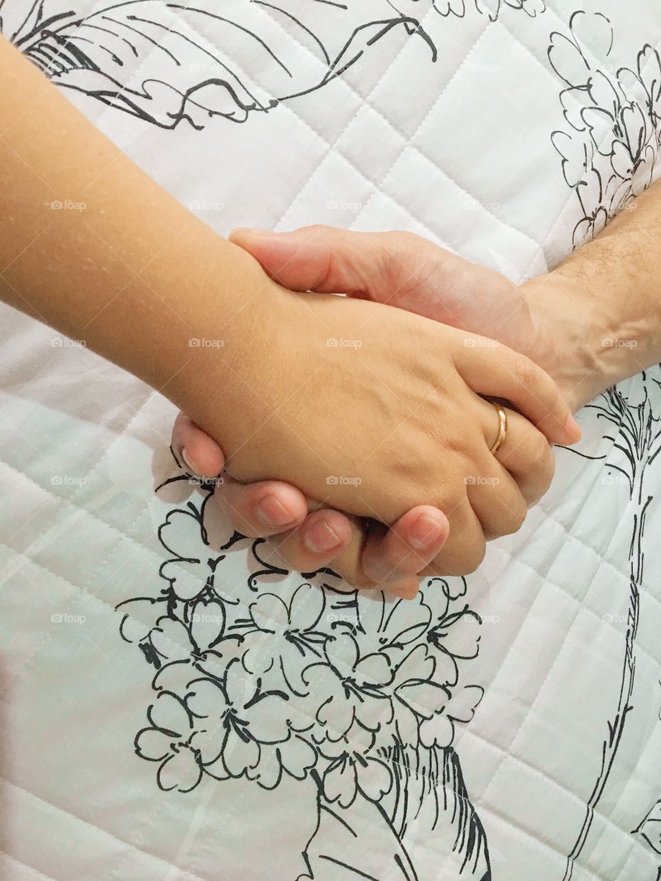 Man and woman holding hands on bed