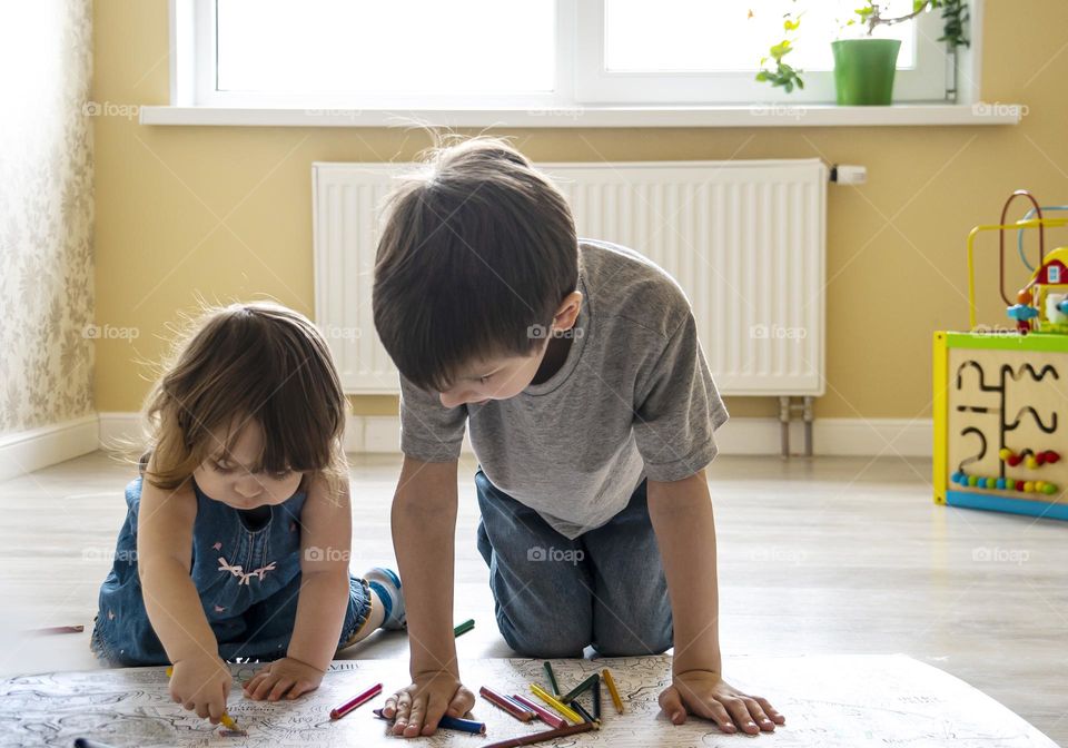 children paint a large coloring book on the floor. leisure at home concept