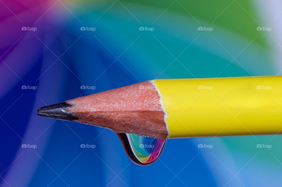 Yellow colored pencil with multicolour background.