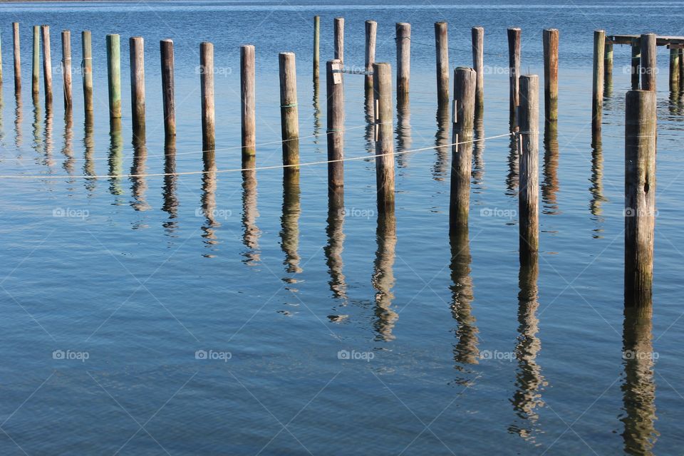 Wooden poles reflecting in water 