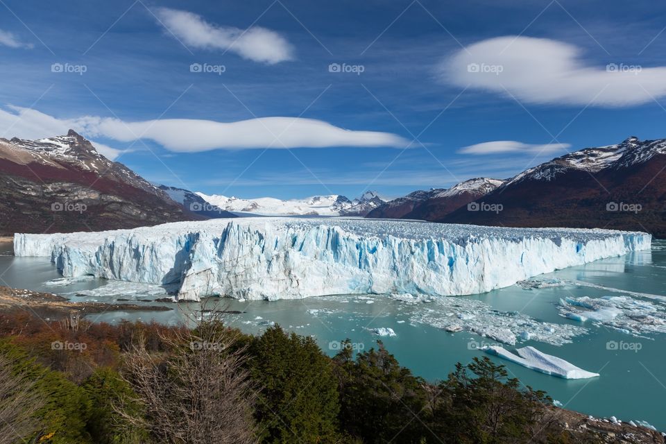 Los Glaciares National Park. Photo of Argentinian glacier. Blue sky and Mountains in the background. Icebergs floating in the water