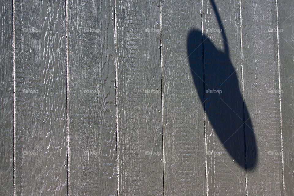 A shadow of an outside wall light attached to an erected wooden wall in New York City.