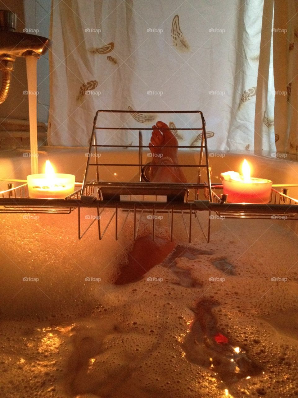 Relaxing in the bathtub with bubbles and candles