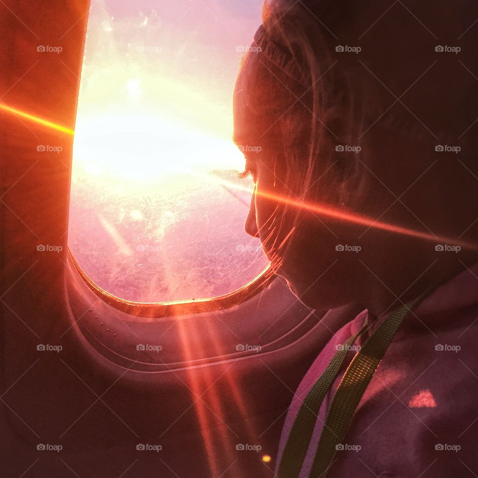 Young girl looking out airplane window 