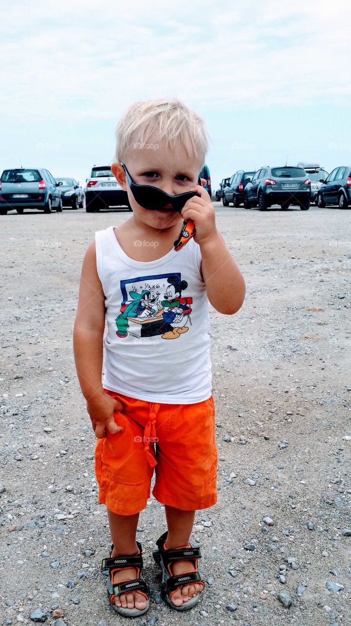Kid att parking lot with toy car in hand