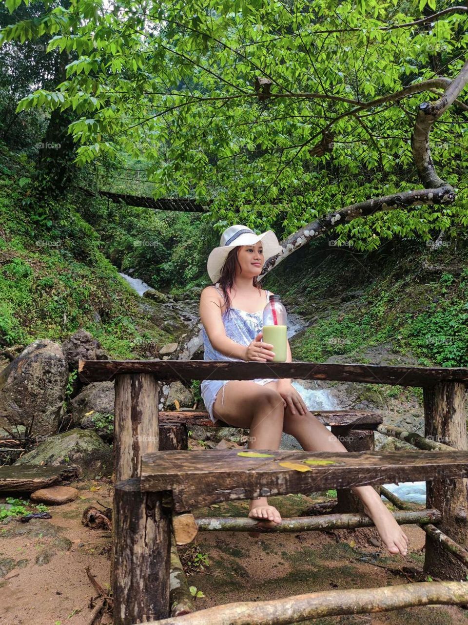 Portrait of woman sitting against waterfall