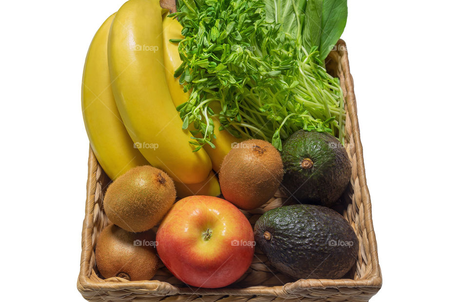 Fresh vegetables and fruits in a basket such as: bananas and kiwis, wheat germ, avocado, spinach and apple