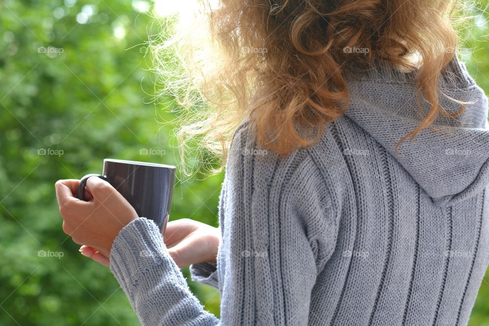 cup of tea in the hands drink on a green nature summer time