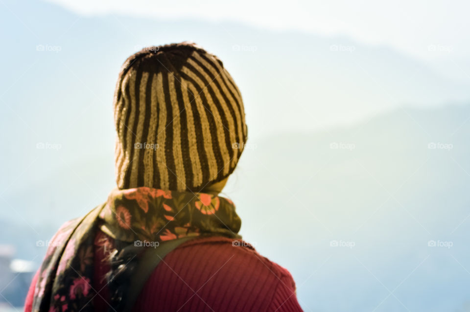 Beautiful girl in summer vacation in woolen hat in sunny day. Woman traveler looking at amazing mountain, Back view. Wanderlust travel concept.