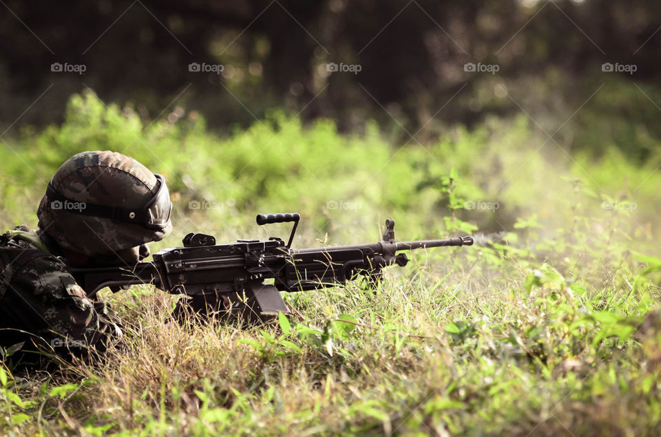 Soldier firing machine gun in the forest.