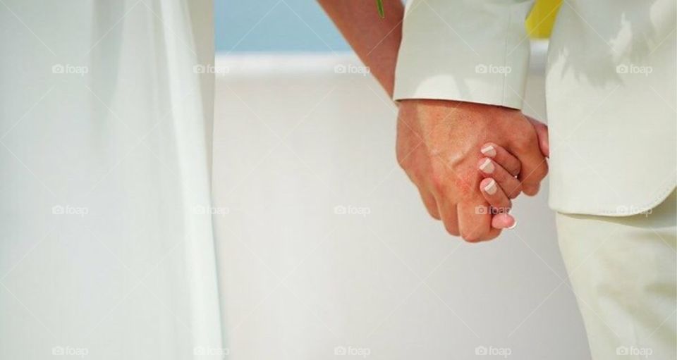 Midsection of bride and groom holding hands