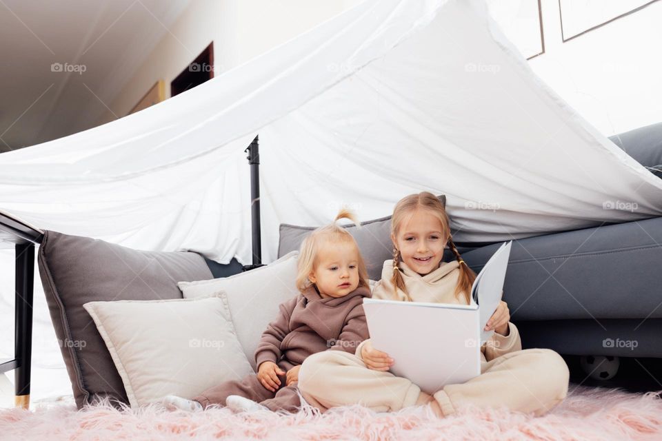 Siblings reading book at home 