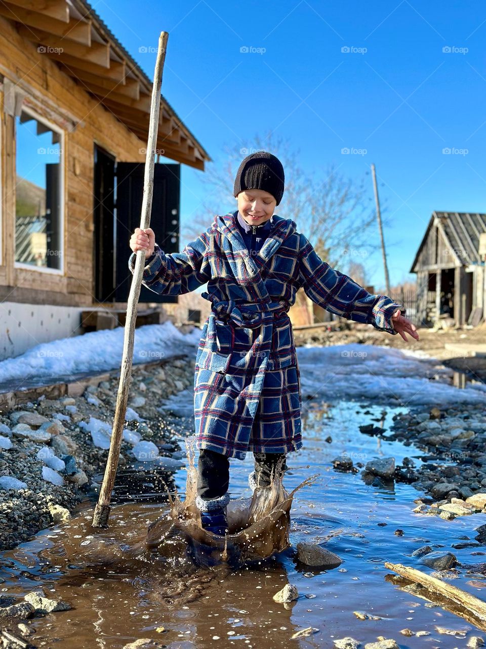 Battle: winter and spring. Boy stomping in a puddle
