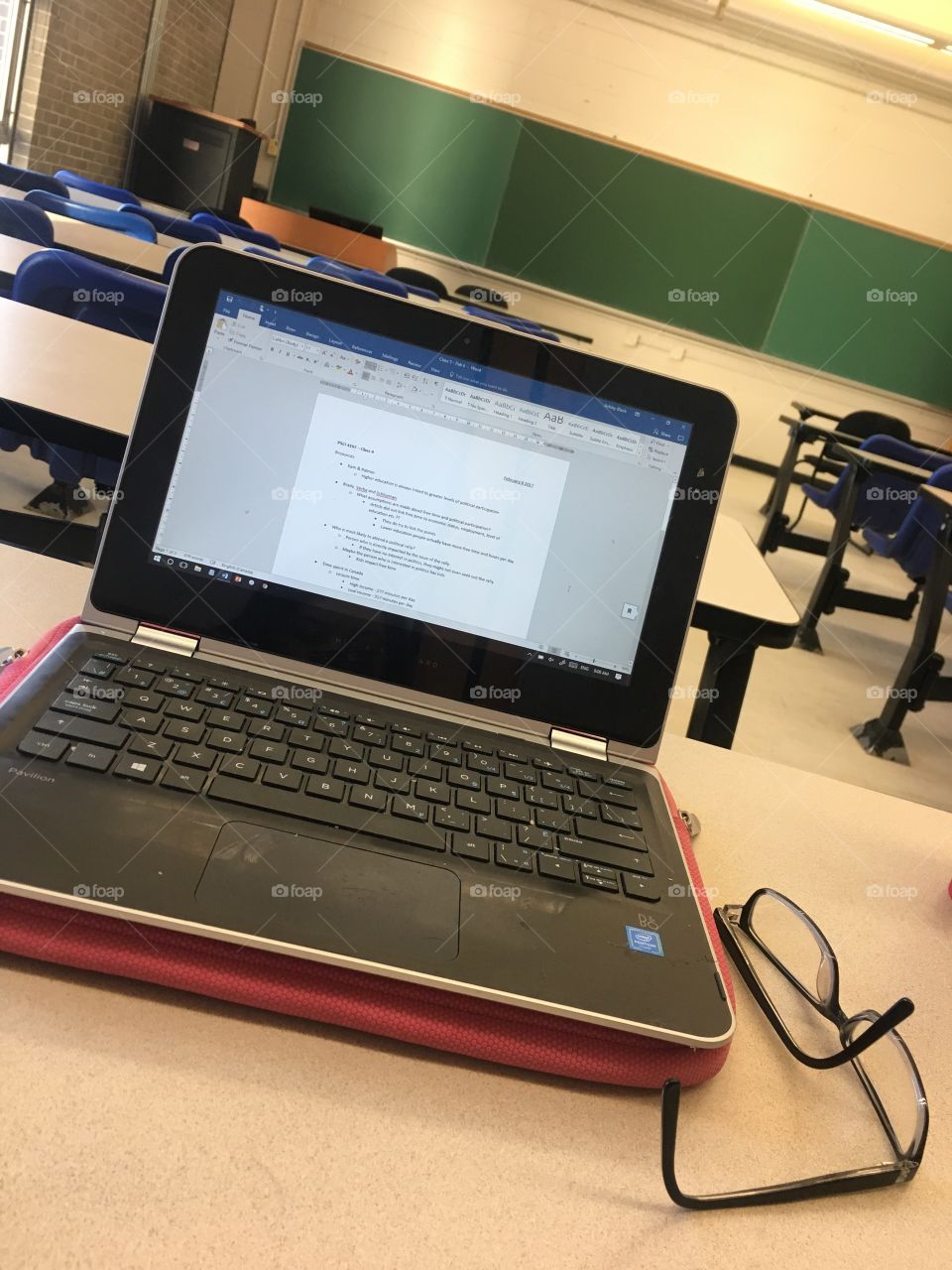 Laptop with notes in an empty classroom