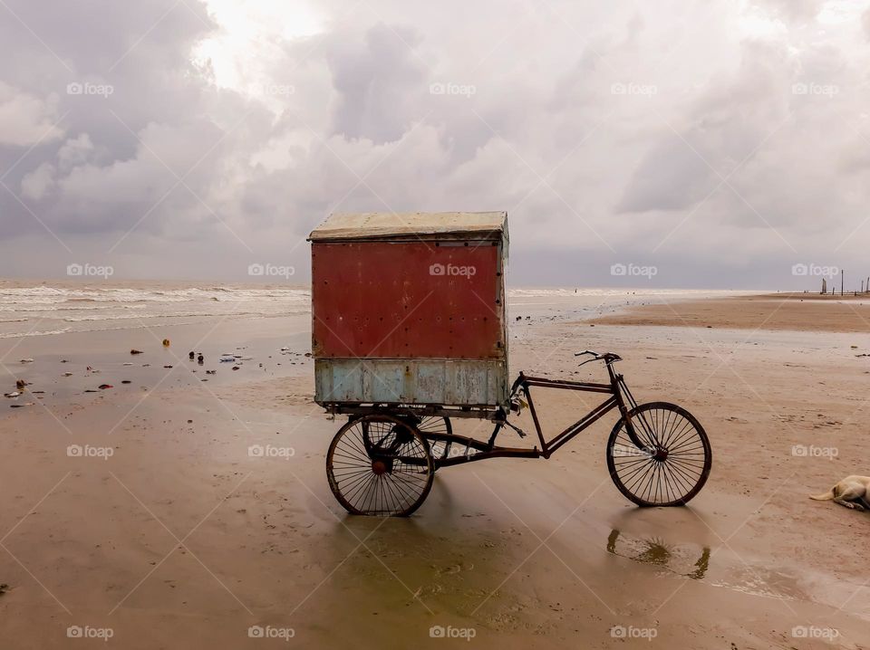 Three wheeled bicycle standing on the sea shore of Ganga Sagar