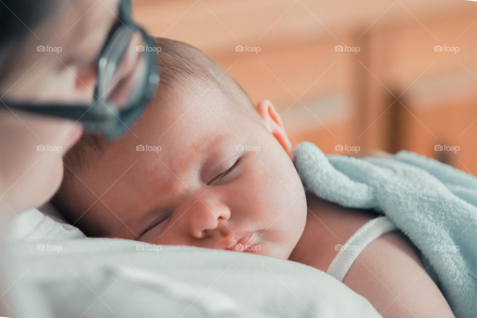 A close-up side view of a gently sleeping baby on the mother's chest.