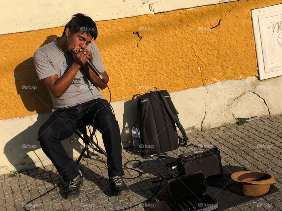 A busker play harmonica in the street, drenched in the late afternoon sunshine - Porto - Oct 2019