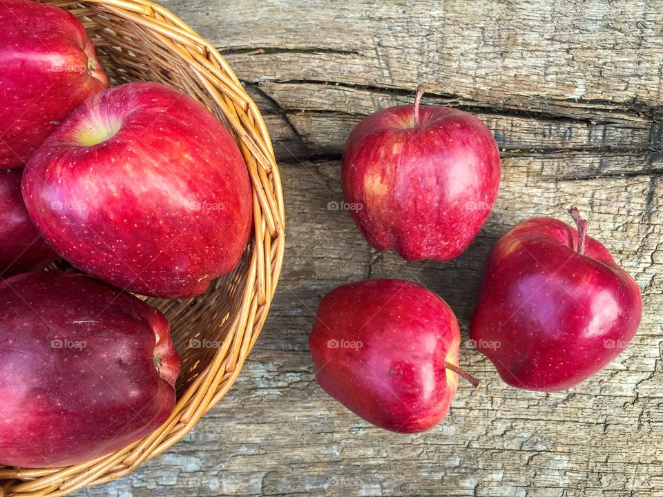 Red apples in a basket and red apples on wooden table