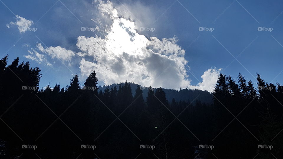 Almaty mountains with sun hidden behind cloud