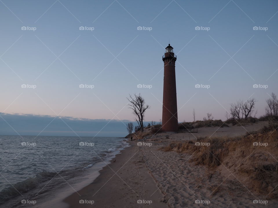 Lighthouse at a beach on Lake Michigan during the sunset 