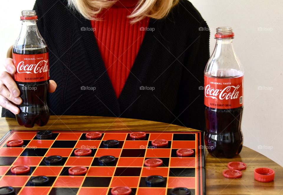 Woman playing checkers and drinking Coca-Cola 