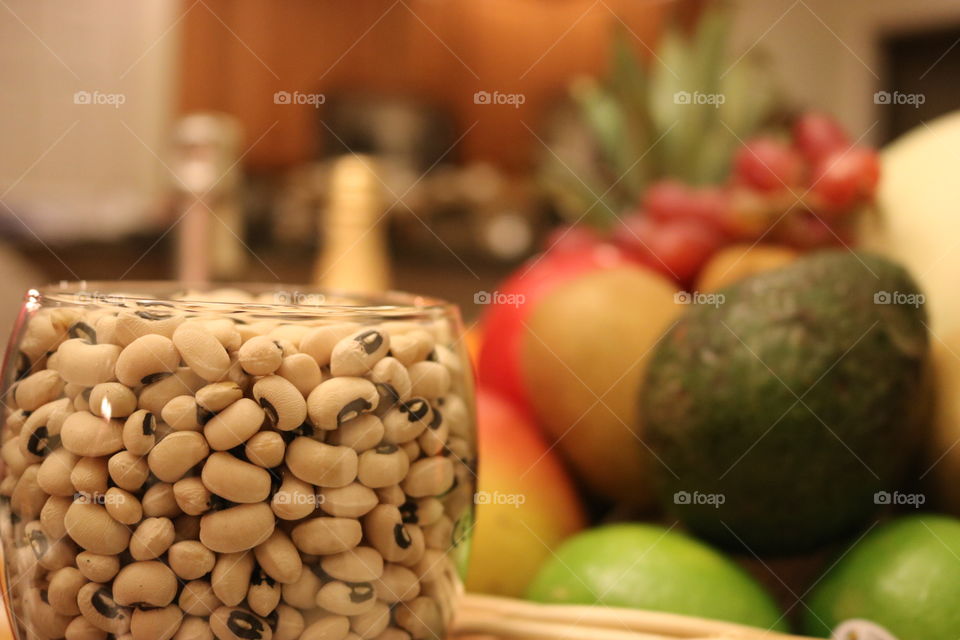 A glass of black eyed peas with various fruits in the background 
