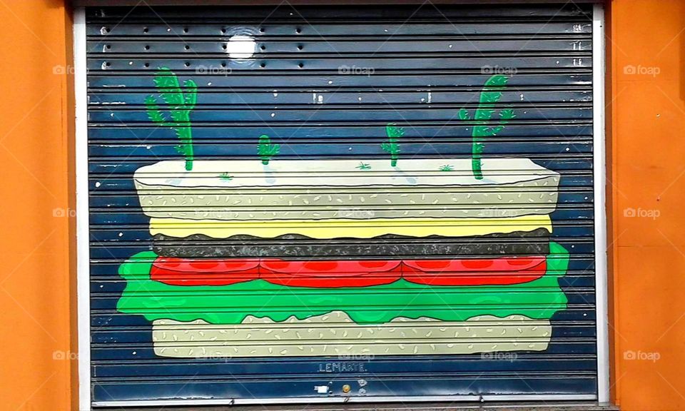 Color Clash: street art depicting a sandwich as the Earth, with cactus growing on top.