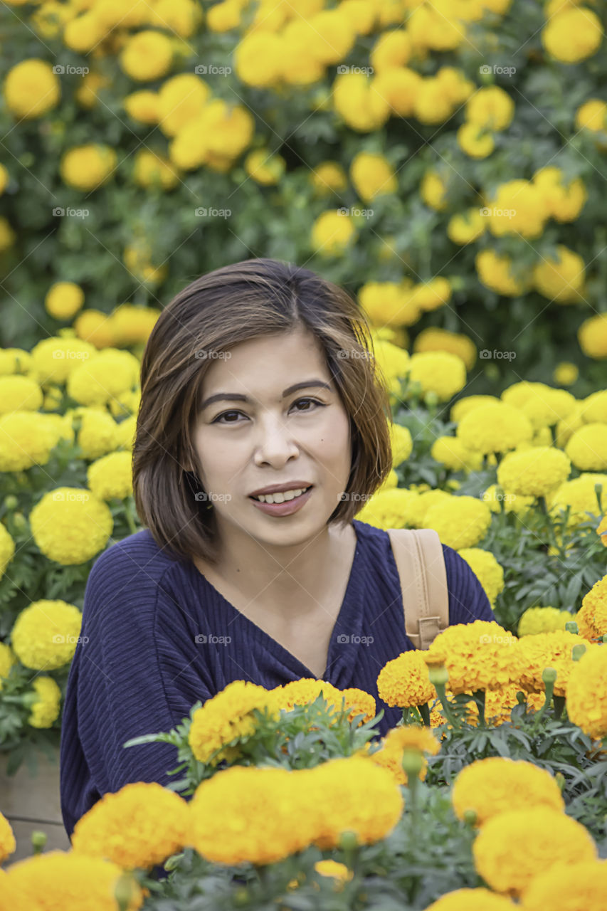 Woman in Yellow Marigold flowers garden or Tagetes erecta in garden