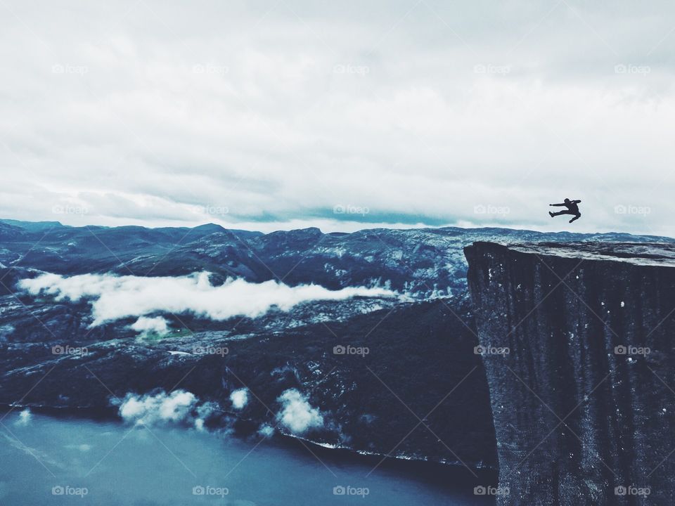 Hiking and victory jump on the top of Prekestolen rock in Norway.