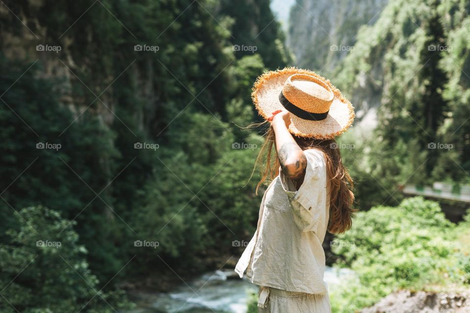 Young woman in straw hat on beautiful view of mountain river 