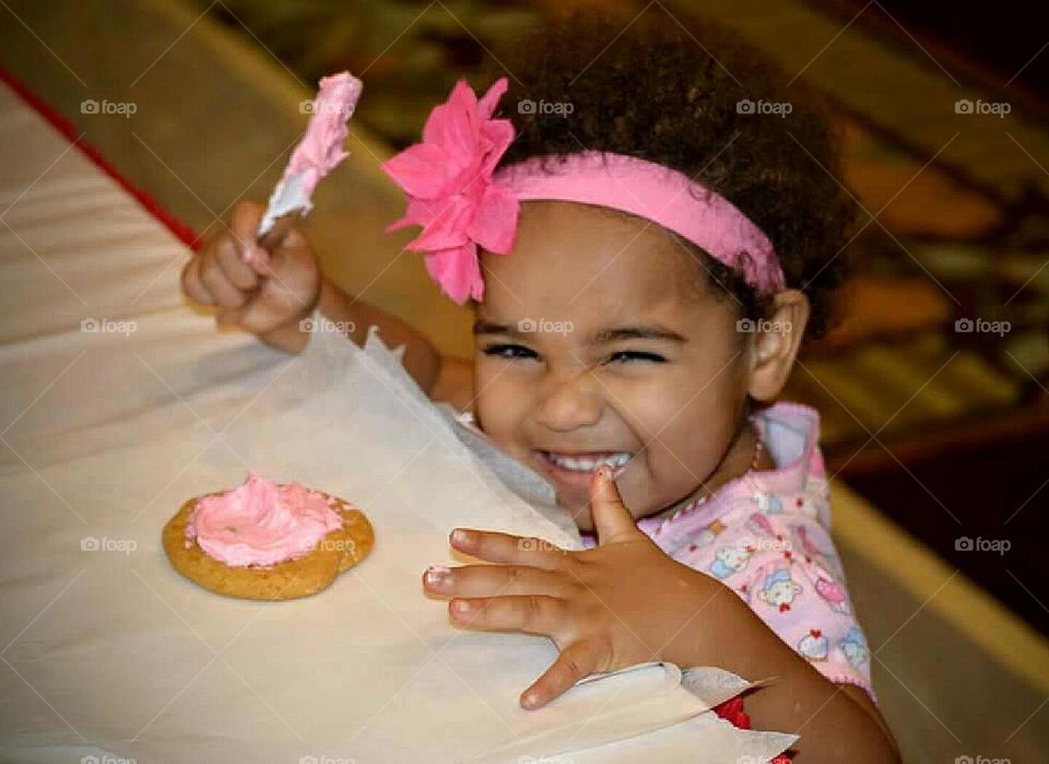 Happy girl frosting her own cookie.