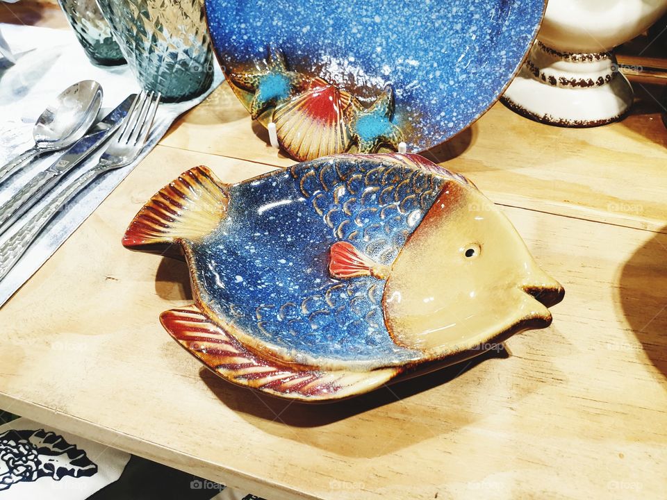 The fish-shaped ceramic plate is decorated on the table.