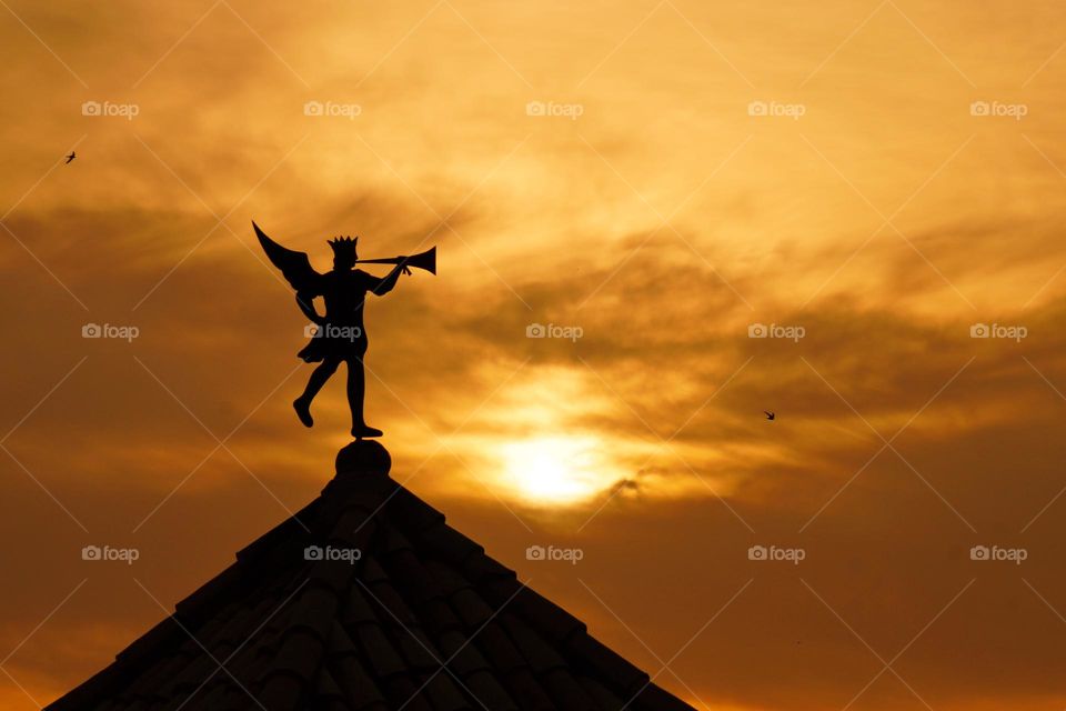 Weather vane in the form of a trumpeter at sunset