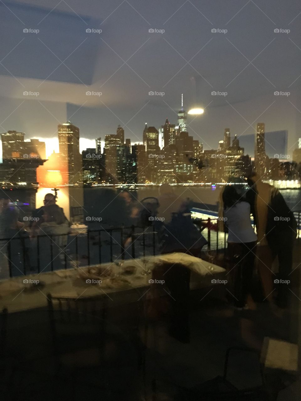 Dinner party in 2017 at an elite home on Pierrepoint Place in Bklyn, NY with magnificent views from the balconies. Reflecting in the window the Manhattan skyline with Empire State while the guests can be seen through the glass. Hypnotic Productions