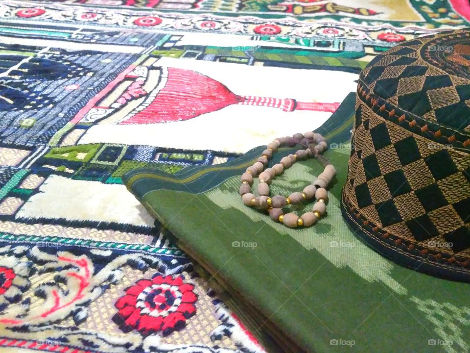 Cap and sarong on prayer rug