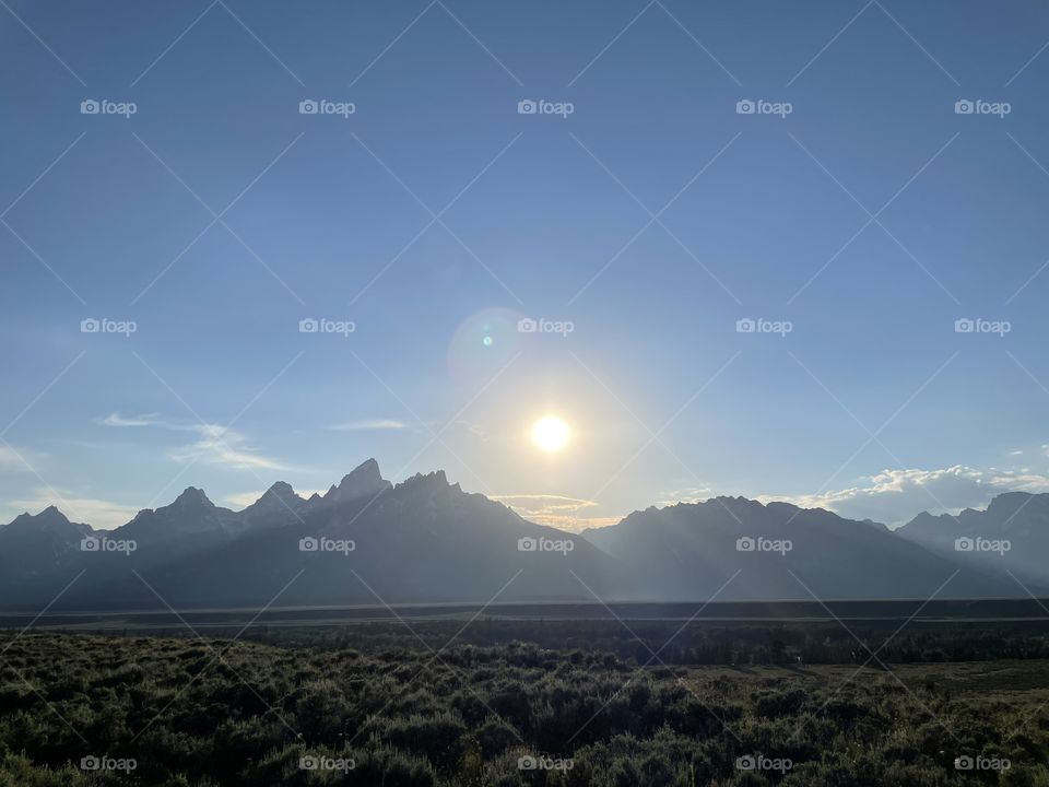 Sunsetting sunset sun over mountain mountains view scenic land prairie landscape fields bushes sky blue clouds sunrise