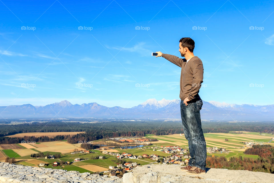 Man photographing landscape using mobile phone